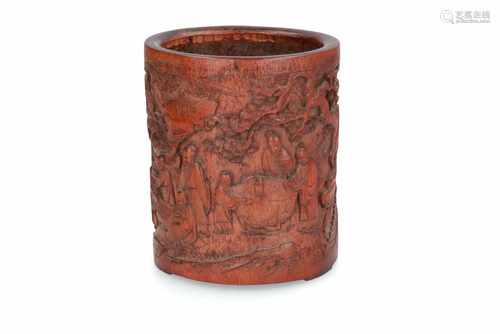 A bamboo brush pot with carved decor of figures around tables in a mountainous landscape with trees.