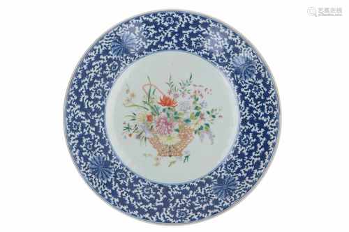 A large blue and white porcelain charger, with in the centre a polychrome decor of flowers. Marked