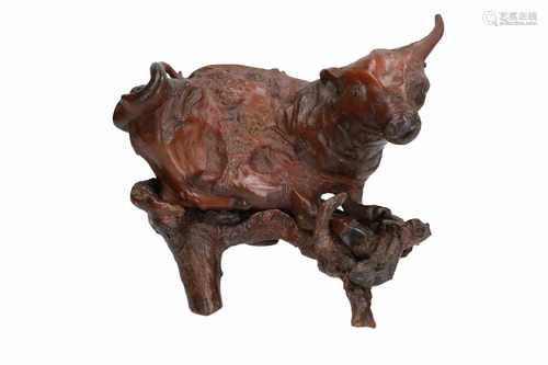 A carved wooden sculpture of a cow, on base made of a tree root. China, 20th century. L. ca. 29 cm.