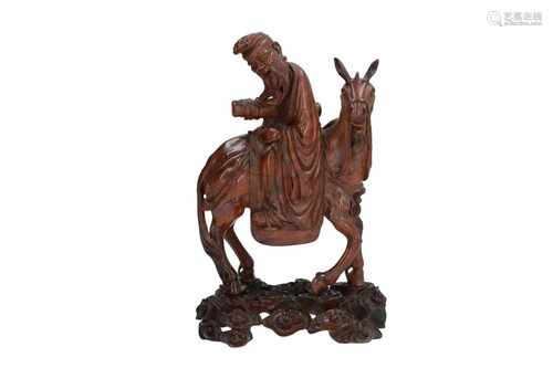 A carved wooden sculpture on wooden base, depicting one of the eight immortals (Zhang Guolao) riding