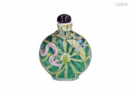 A polychrome porcelain snuff bottle with amethyst stopper, decorated in relief with lotus leaves and