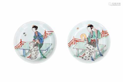 A pair of polychrome porcelain saucers, decorated with a lady in a garden, holding a mirror.