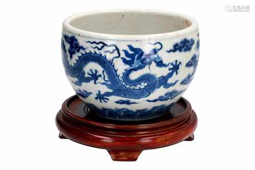 A blue and white porcelain bowl on wooden base, decorated with dragons and clouds. Marked with