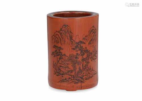 A bamboo brushpot with carved decor of a mountainous landscape, and relief decor of characters.