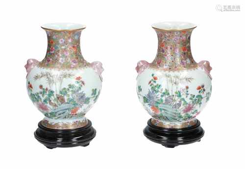 A pair of polychrome porcelain vases on wooden base, decorated with flowers and birds. Handles in