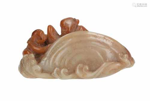 A jade sculpture depicting two figures with fish in a shell. China, 18th/19th century. L. 11 cm.