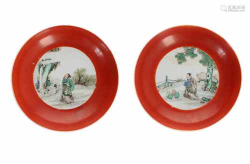 A pair of Famille Verte porcelain saucers with coral red rim, decorated with figure in landscape.