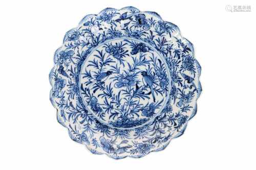 A blue and white porcelain saucer with lotus-shaped scalloped rim, decorated with flowers and birds.