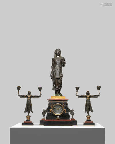 the central figure cast after the model by Emile-Louis Picault (French, 1833-1915), the movement stamped Japy Freres, the set retailed Georges Servant A good late 19th century French parcel gilt and patinated bronze and rouge and black marble three-piece figural clock garniture in the Egyptian revival taste