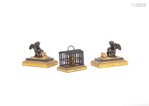 A Regency gilt and patinated bronze model of a caged Cupid together with a pair of similar period figural mantel ornaments of Cupids