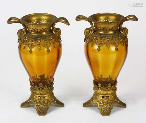 Continental amber glass urns, each having a Classical form with gilt metal handled sides accented