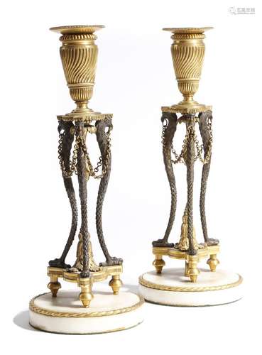 A pair of early 19th century gilt and patinated bronze candlesticks, each with a detachable drip-pan