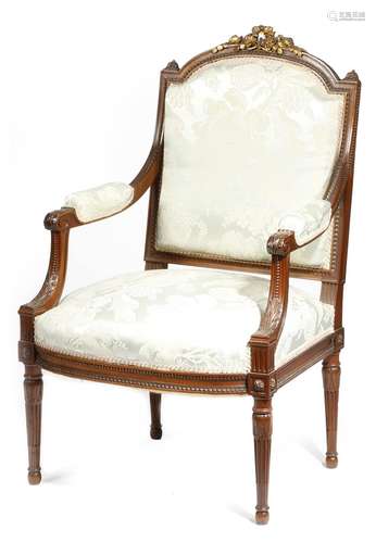 A French walnut and parcel gilt fauteuil in Louis XVI style, the padded back, seat and armrests