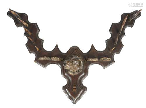 A late 19th century Black Forest style wall hanging whip rack, carved and painted with the head of a