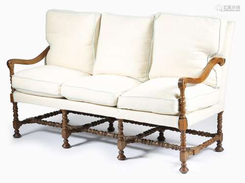 A William and Mary style oak three seater settee, upholstered in cream wool, with scroll arms, on