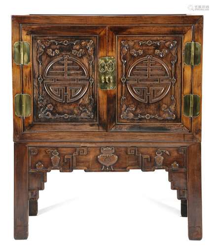 A Chinese hardwood cabinet on stand, of panelled construction, with a pair of cupboard doors