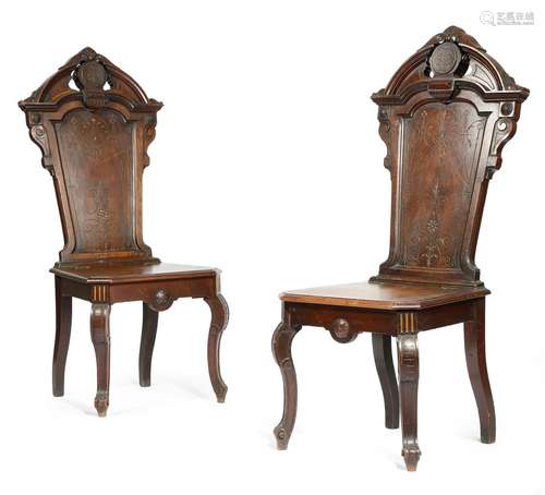 A pair of Victorian walnut and parcel gilt hall chairs, each with an architectural panelled back