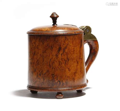 A Norwegian burr birch tankard, the hinged lid with a turned finial, with a scroll handle with brass