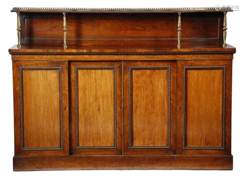 λ A Regency rosewood side cabinet, with nulled decoration, the raised top with a gilt brass