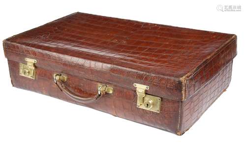 An early 20th century crocodile leather suitcase by Army & Navy, the hinged lid with gilt