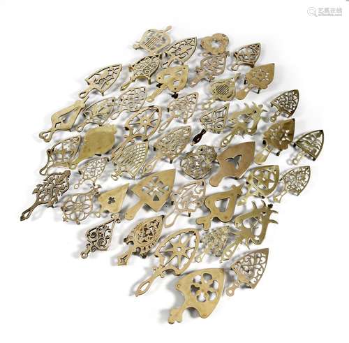 A large collection of 19th century brass trivets, pierced, with various designs and motifs,