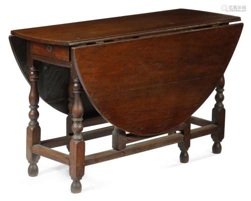 A Queen Anne oak gateleg table, the oval drop-leaf top above a frieze drawer to either end, on