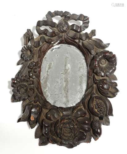 A small 18th century carved wood mirror, the oval plate within a carved frame, with ribbon tied