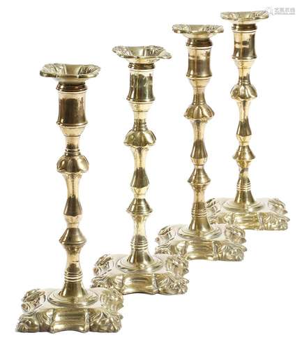 A set of four early 19th century brass candlesticks, each with a detachable drip-pan, above a