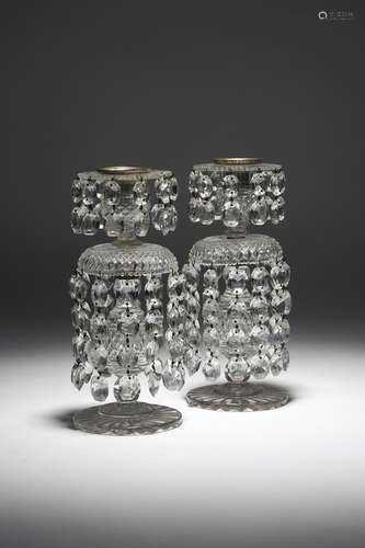 A pair of early 19th century cut-glass lustre candlesticks, each with a detachable drip-pan and hung