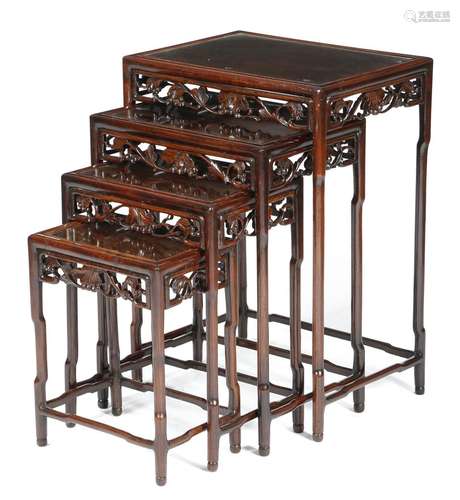 A quartetto nest of Chinese padouk occasional tables, each with an inset glass top, above a carved