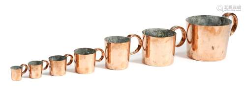 A harlequin set of seven copper navy rum or 'grog' measures, with loop handles, comprising: 1