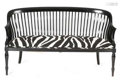 A late 19th century ebonised two seater settee, with a curved slatted back, above a zebra skin