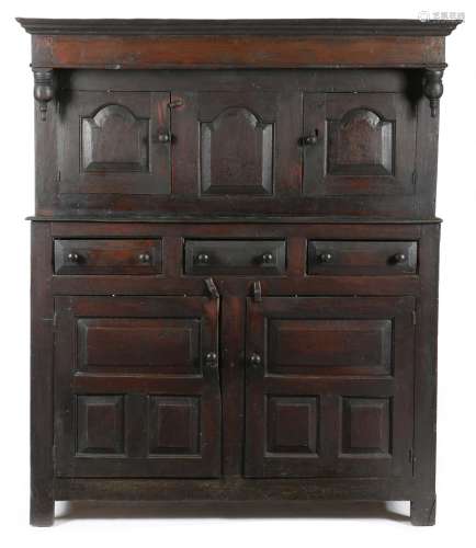 An early 18th century Welsh oak press cupboard, the plain frieze with turned pendants, above a