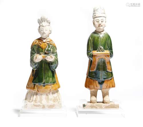 Two Chinese glazed pottery figures of attendants, wearing tunics, boots and hats and holding