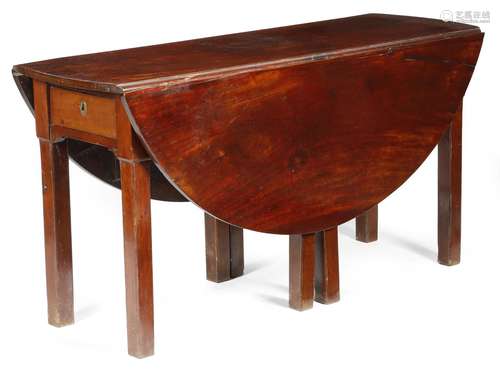 A George III mahogany wake style dining table, the oval drop-leaf top above a frieze drawer to