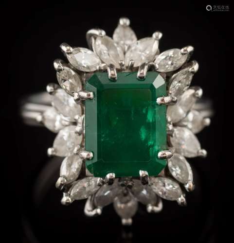 An emerald and diamond cluster ring: the central, rectangular emerald approximately 10mm long x 7.
