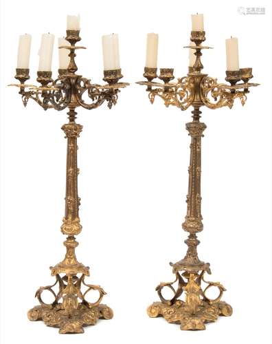 A pair of gilt metal five-light candelabra: with urn-shaped nozzles on scrolling arms,