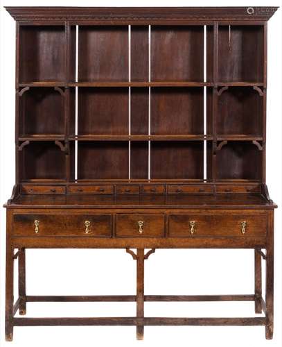 An 18th century oak dresser: with a later shelved superstructure having a moulded and foliate