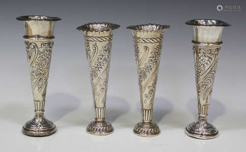 A pair of late Victorian silver specimen vases, each with spiral floral and foliate decoration, on a