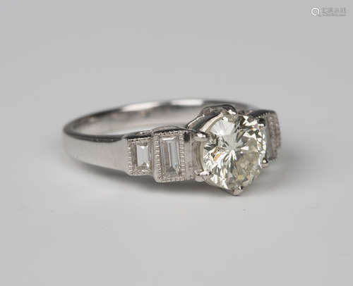 A platinum and diamond ring, claw set with the principal circular cut diamond between stepped