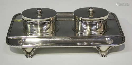 A George V silver rectangular inkstand, fitted with two oval inkwells with hinged lids, flanked by