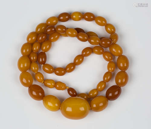 A single row necklace of fifty-one graduated oval butterscotch and honey coloured mottled opaque