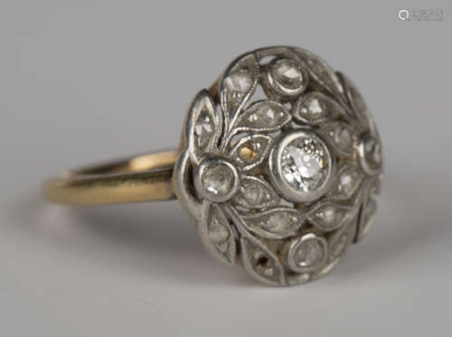 A gold and diamond cluster ring of shaped circular form with foliate motifs, mounted with a