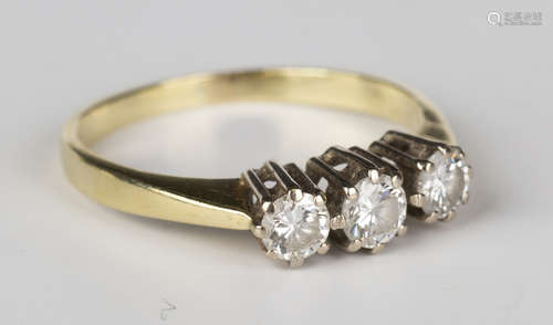 An 18ct gold and diamond three stone ring, claw set with a row of circular cut diamonds, ring size