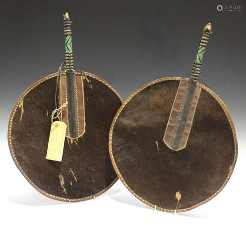 A pair of late 19th/early 20th century Zulu animal hide circular fans, the handles bound in leather,