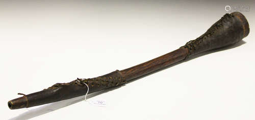 An early 20th century Sudanese carved wooden horn with two applied leather sleeves, length 89cm.