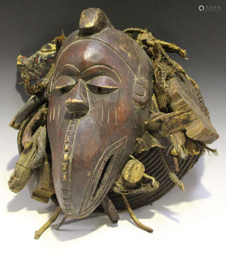 An African carved and painted wooden mask, modelled with a large beak, mounted on a raffia and