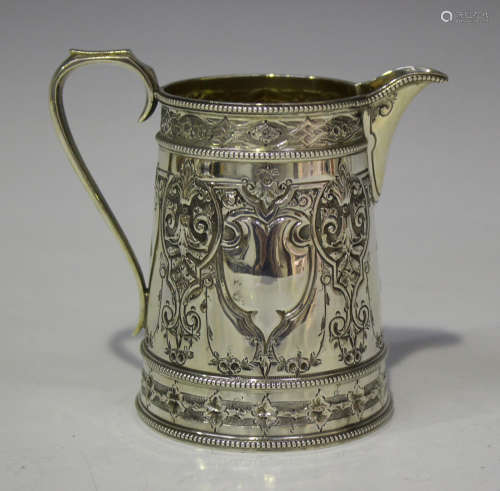 A Victorian silver cream jug of tapering cylindrical form, decorated in relief with opposing
