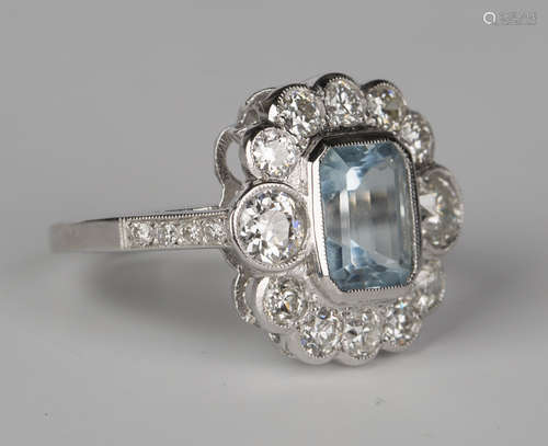 A white gold, aquamarine and diamond cluster ring, mounted with an emerald cut aquamarine within a