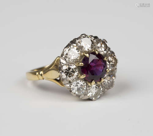 A gold, ruby and diamond nine stone cluster ring, claw set with the circular cut ruby within a